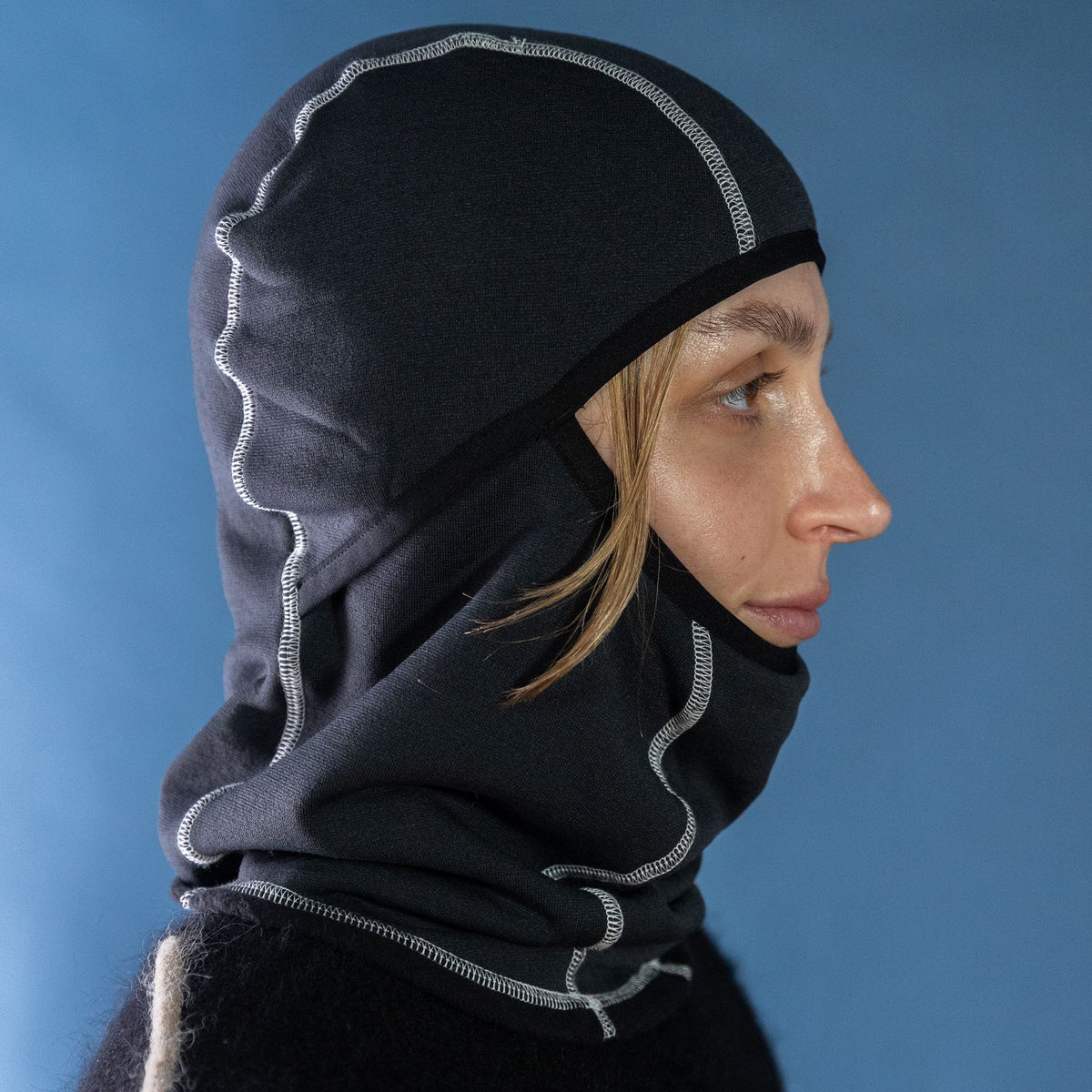Woman wearing the Thurston Power Wool™ Balaclava in glacier grey / black, side profile studio portrait